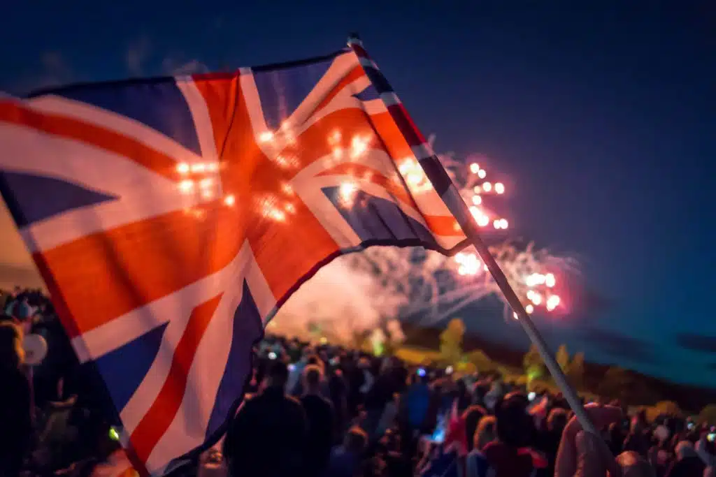 Union Jack flag flying over crowds in the UK.